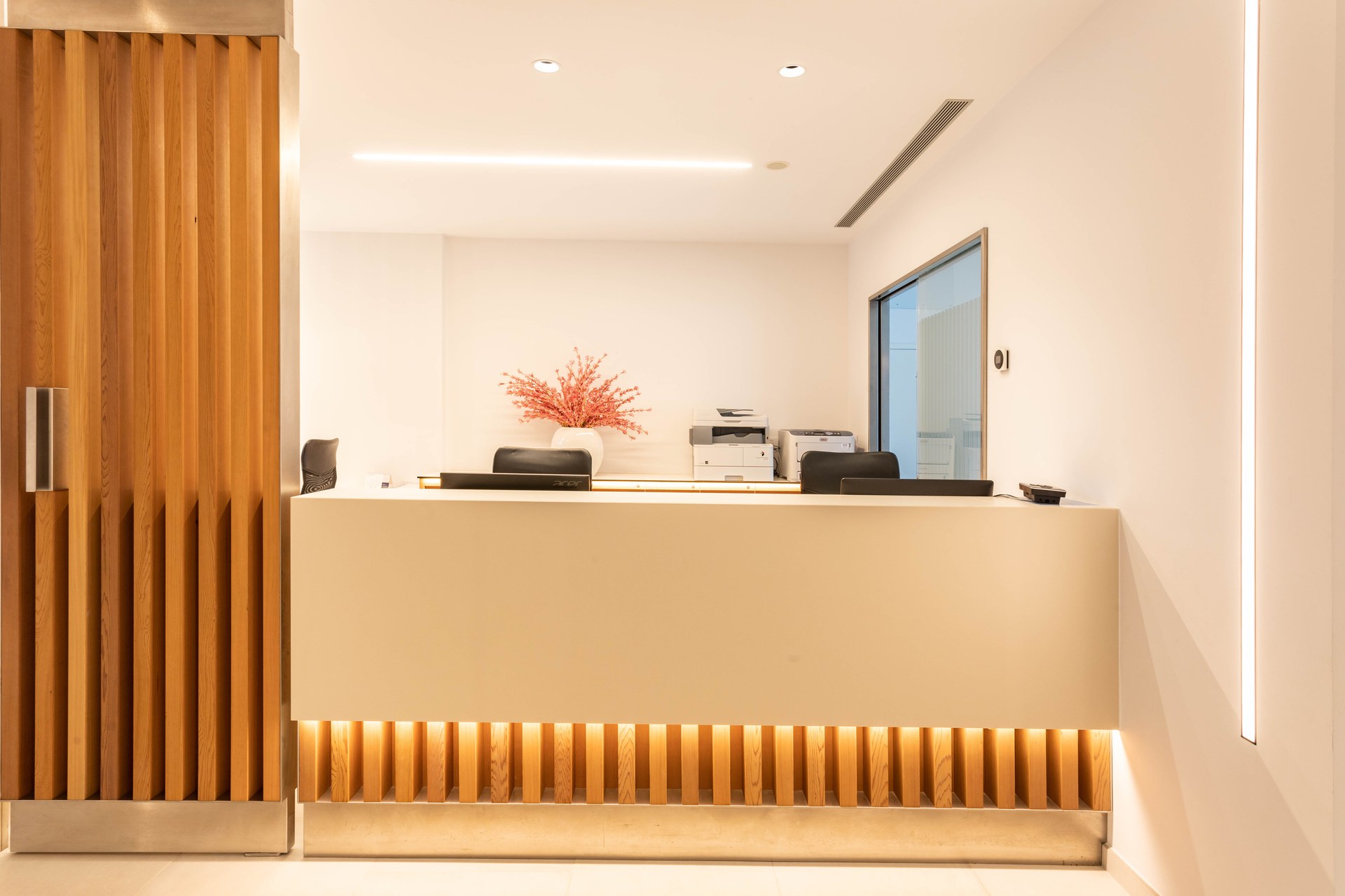 Recepció amb taulell il·luminat i lames de fusta, Clínica Mir i Andreu
