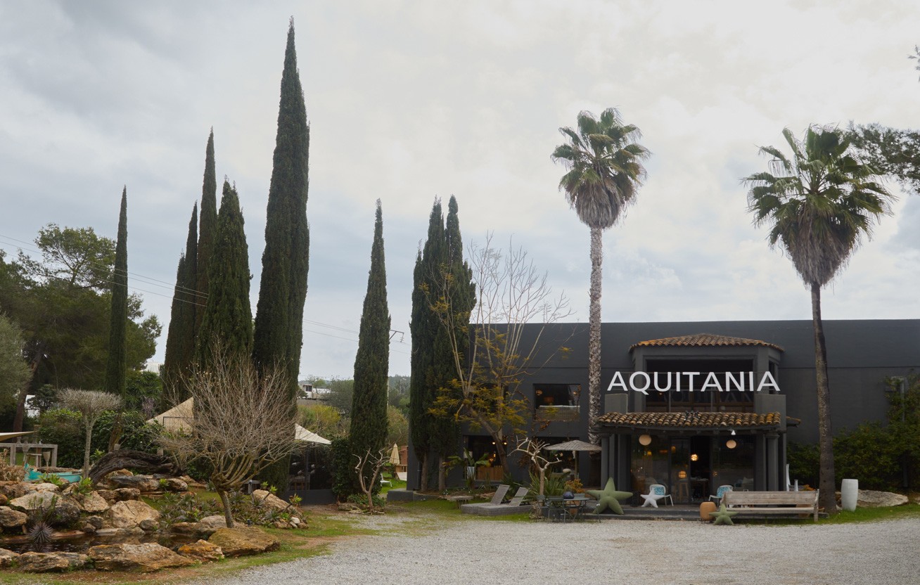 Extérieur de la boutique Aquitania à Ibiza entre palmiers et cyprès