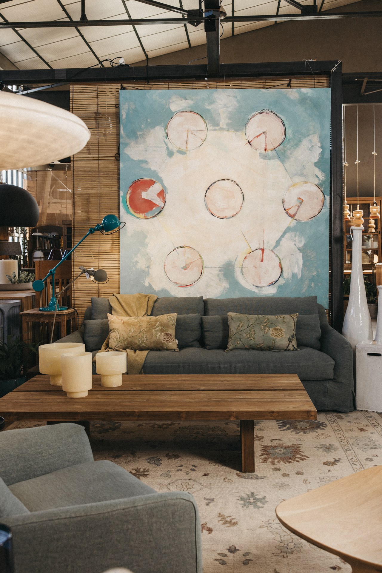 Canapé gris, table en bois et tableau grand format dans la boutique de Maó