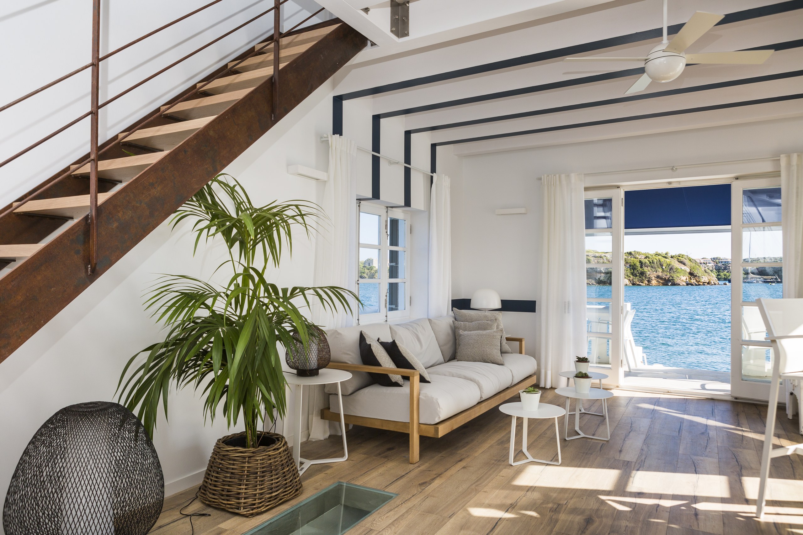 Saló amb escala de fusta i vistes al port, projecte Casa Venecia