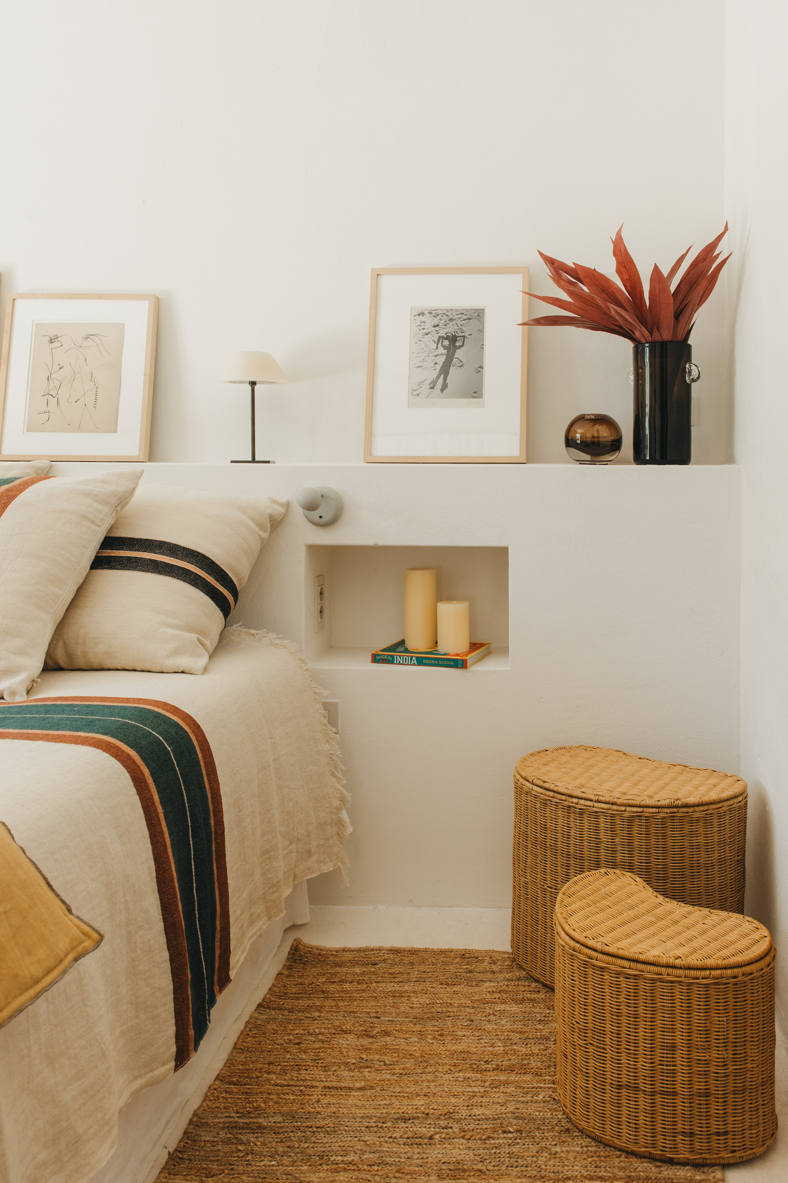 Chambre avec couvre-lit rayé, niches murales et tabourets en fibre